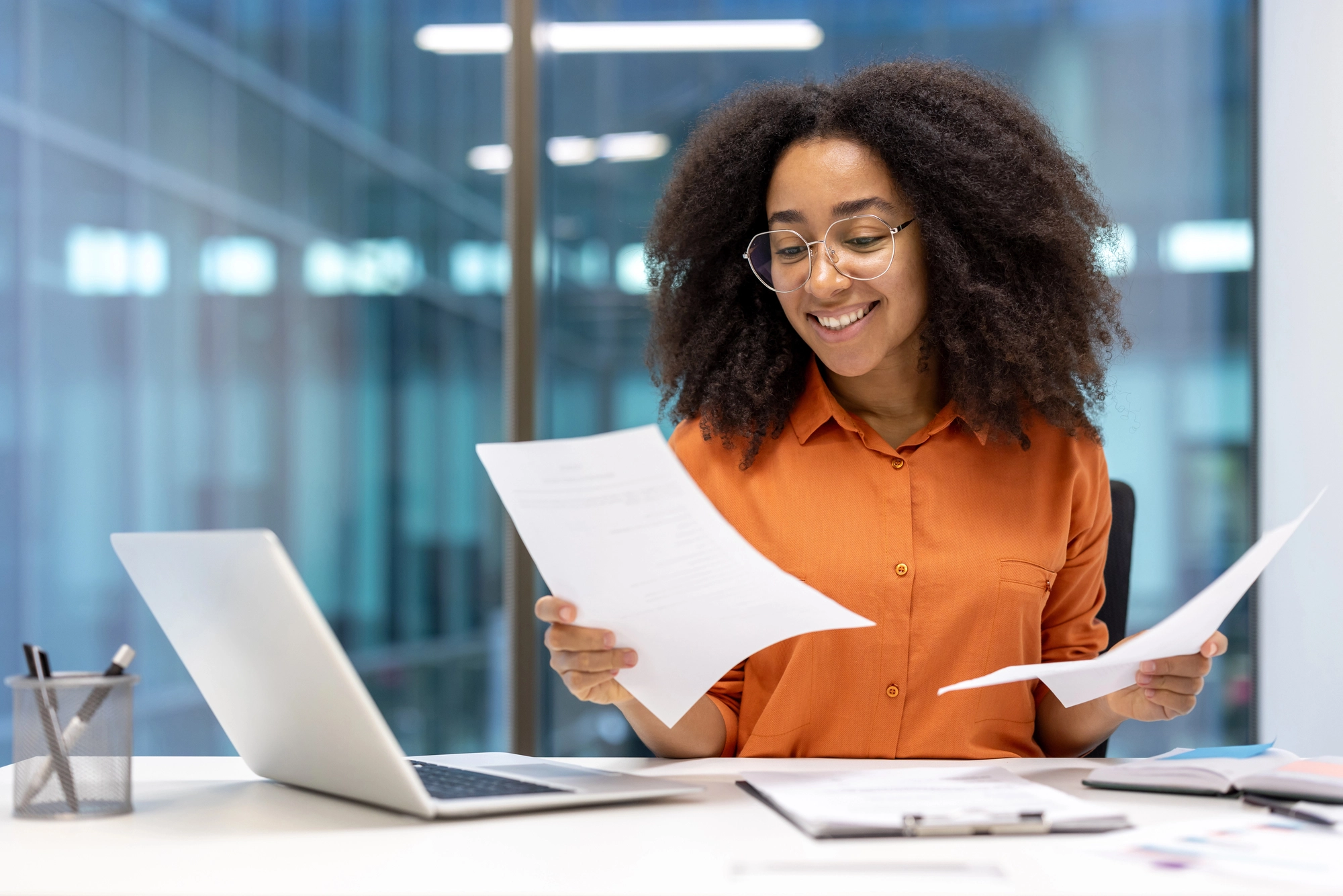 Une jeune femme compare deux documents à son bureau